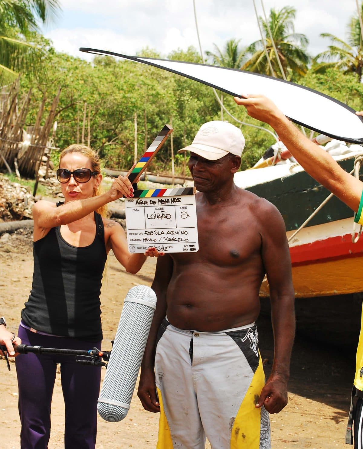 Equipe da Obá Cacauê em set de filmagem numa praia, com claquete em primeiro plano